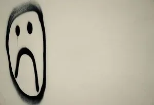 Smiley triste peint à la bombe sur un mur clair