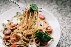 Spaghettis enroulés sur une fourchette, avec tomates et basilic