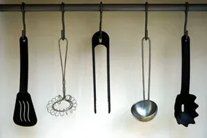 Ustensiles de cuisine noirs et inox suspendus à une barre