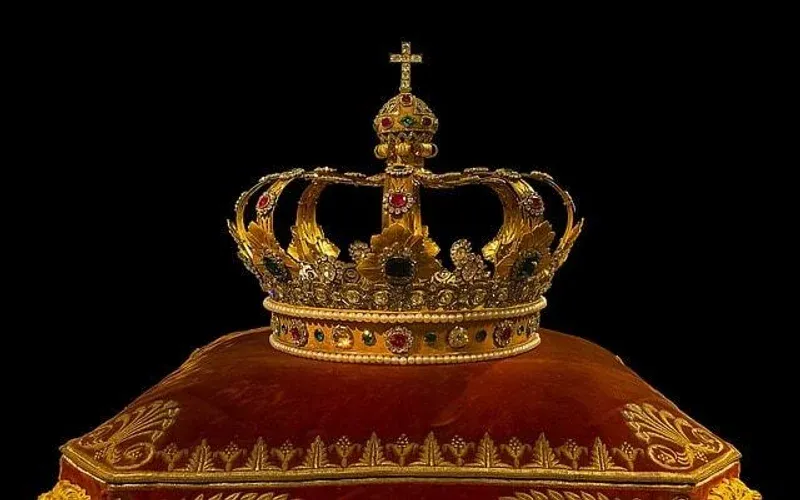 A jewelled crown on a velvet cushion