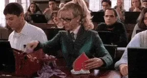 Blonde student in glasses pulls a fluffy pink pen from her bag in a lecture hall
