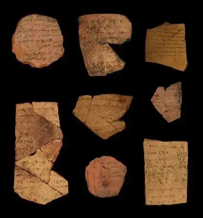 Nine pottery shards with lines of ink writing, laid out on a black ground