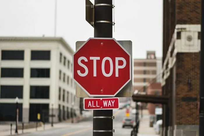 Panneau stop rouge avec la mention All Way sur un poteau, en ville